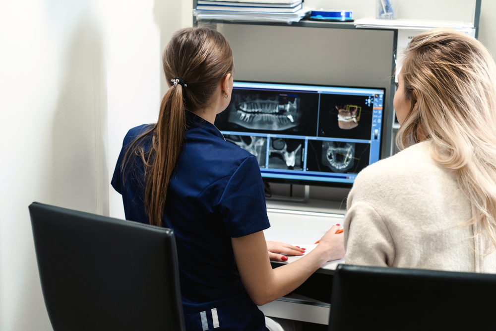 stock-photo-female-doctor-shows-the-patient-an-x-ray-image-at-display-computer-diagnostics-dental-tomography-1401017810